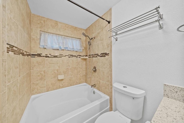 bathroom featuring tiled shower / bath combo and toilet