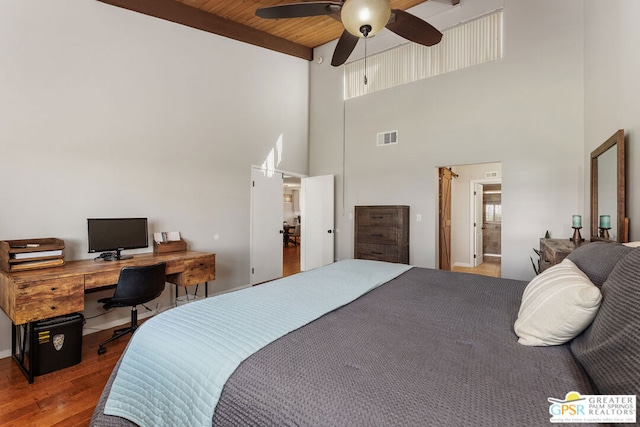 bedroom featuring ceiling fan, ensuite bathroom, a towering ceiling, hardwood / wood-style flooring, and wooden ceiling