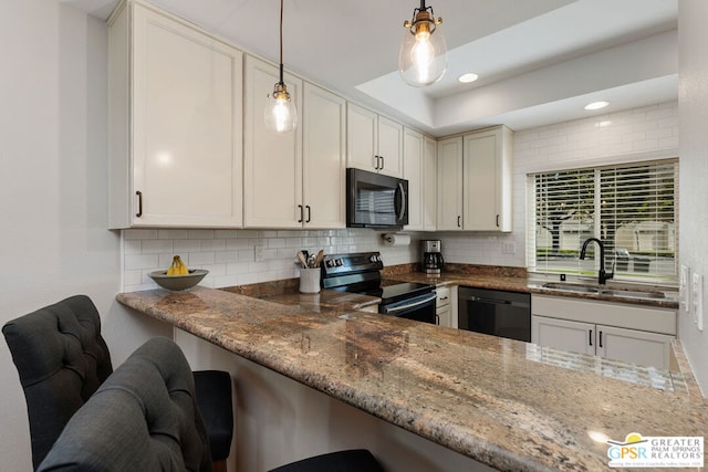 kitchen with light stone counters, sink, pendant lighting, and black appliances