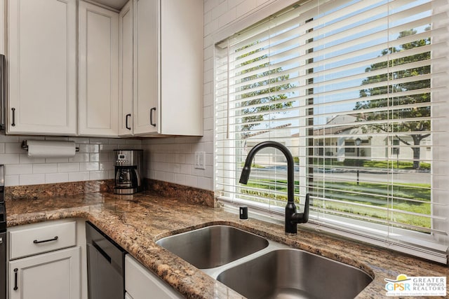 kitchen featuring decorative backsplash, sink, black dishwasher, white cabinets, and dark stone counters