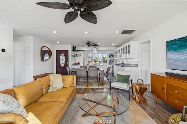 living room featuring hardwood / wood-style flooring, sink, radiator, and ceiling fan