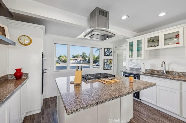 kitchen with sink, dark stone counters, island exhaust hood, and white cabinetry