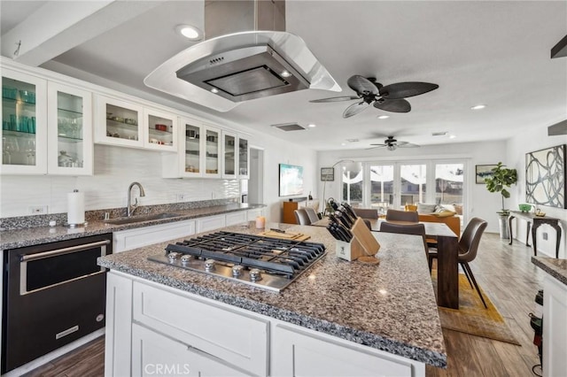 kitchen with stainless steel gas stovetop, white cabinetry, sink, dark wood-type flooring, and a center island