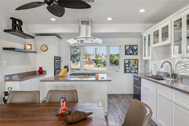 kitchen featuring sink, white cabinets, island range hood, and dark stone counters