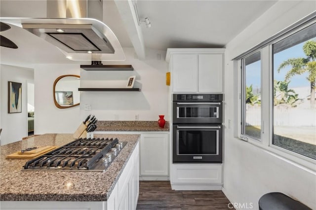 kitchen featuring stainless steel gas cooktop, black double oven, dark stone counters, and white cabinetry