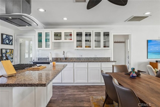 kitchen with a center island, white cabinetry, dark stone countertops, sink, and island range hood