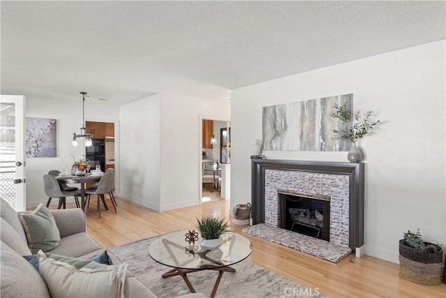 living room featuring light wood-type flooring and a tiled fireplace