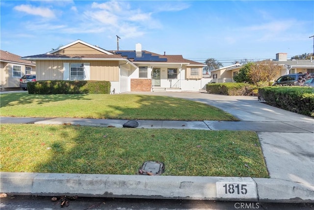 view of front of property with a front lawn and solar panels