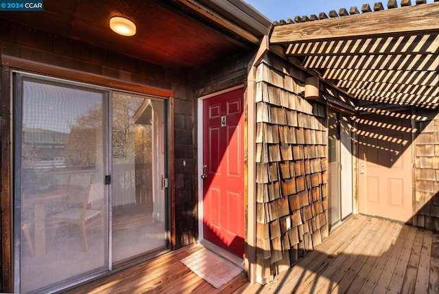 property entrance featuring a pergola and a wooden deck