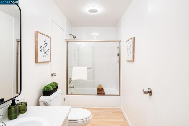 full bathroom with combined bath / shower with glass door, vanity, toilet, and hardwood / wood-style floors