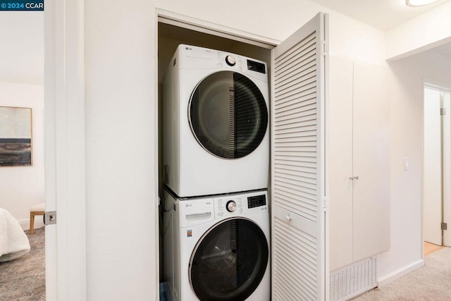 laundry room featuring stacked washer / dryer and light carpet