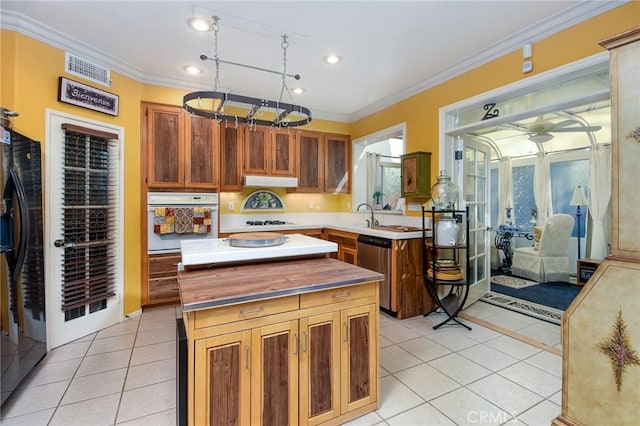 kitchen with light tile patterned flooring, ornamental molding, a center island, and white appliances