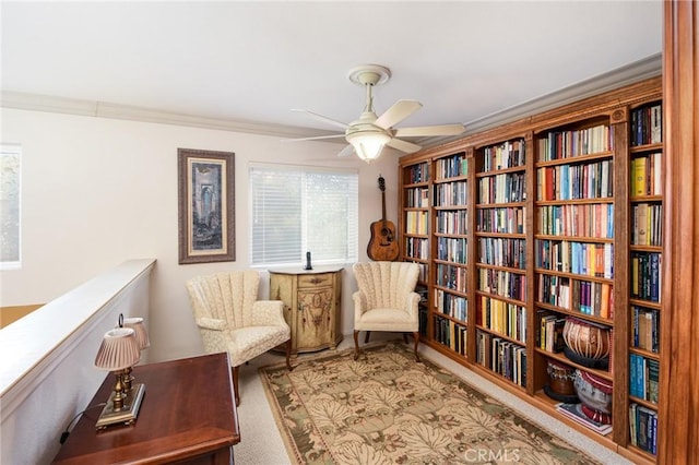 sitting room featuring ceiling fan, light colored carpet, and crown molding