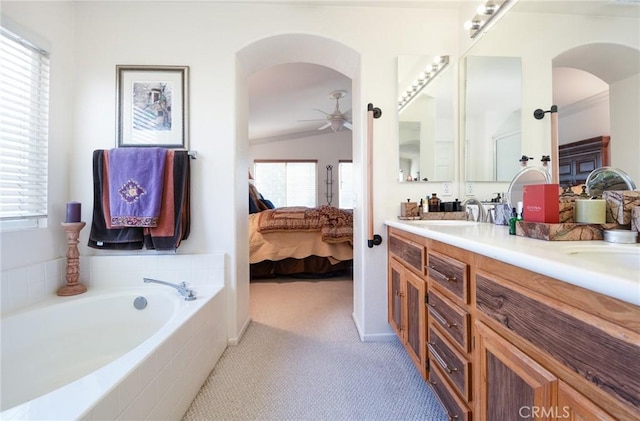 bathroom featuring vaulted ceiling, ceiling fan, a relaxing tiled tub, and vanity