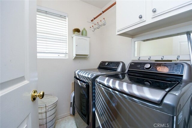 clothes washing area featuring washer and dryer, plenty of natural light, and cabinets