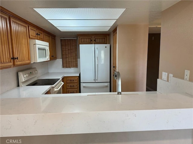 kitchen featuring sink, kitchen peninsula, and white appliances