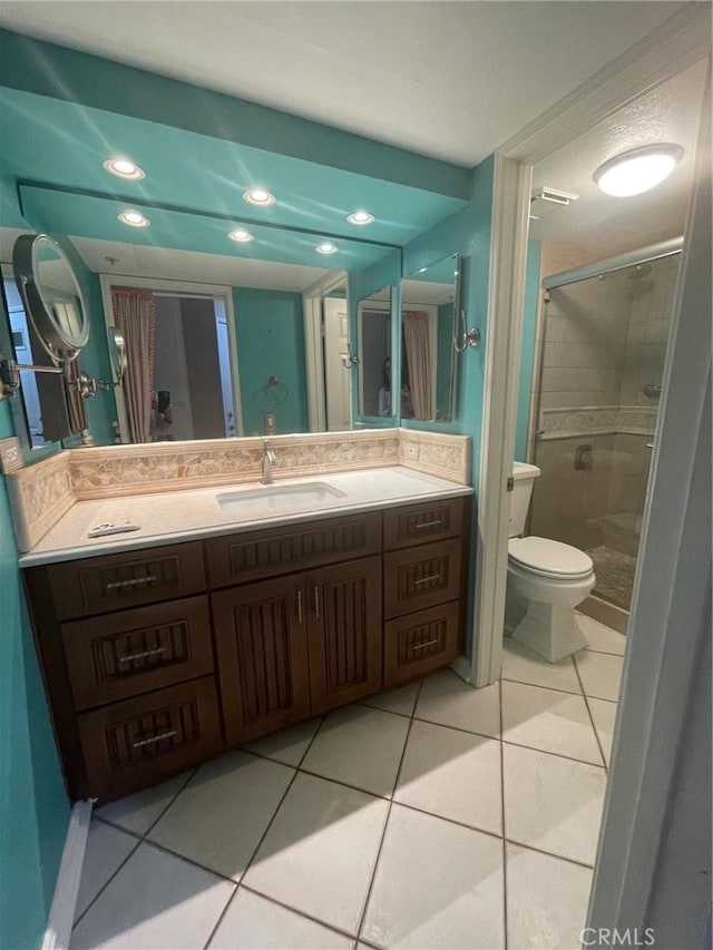 bathroom with toilet, vanity, tile patterned flooring, and a shower with door