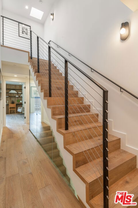 staircase featuring a skylight, a high ceiling, and hardwood / wood-style floors