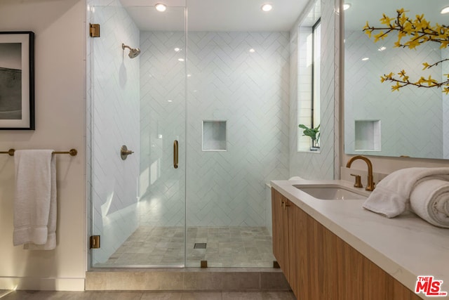 bathroom featuring a shower with shower door and vanity