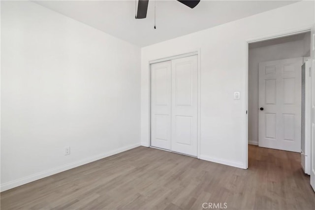 unfurnished bedroom with ceiling fan, a closet, and light wood-type flooring