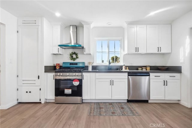 kitchen featuring white cabinetry, wall chimney range hood, and appliances with stainless steel finishes