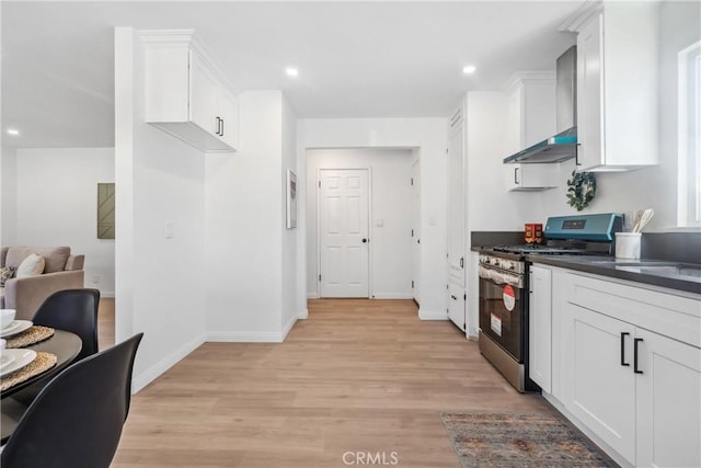 kitchen with light wood-type flooring, white cabinetry, stainless steel range with gas stovetop, and wall chimney range hood