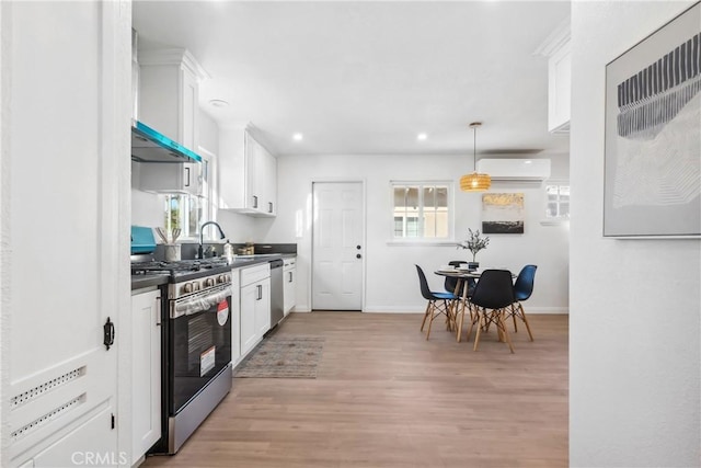 kitchen with hanging light fixtures, a wall mounted AC, appliances with stainless steel finishes, and white cabinetry