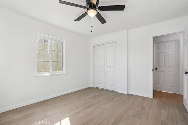 unfurnished bedroom with ceiling fan, a closet, and light wood-type flooring