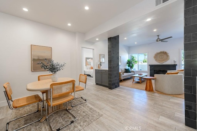 dining room featuring ceiling fan, light hardwood / wood-style flooring, and a fireplace