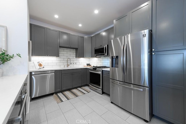 kitchen featuring sink, stainless steel appliances, gray cabinets, and backsplash