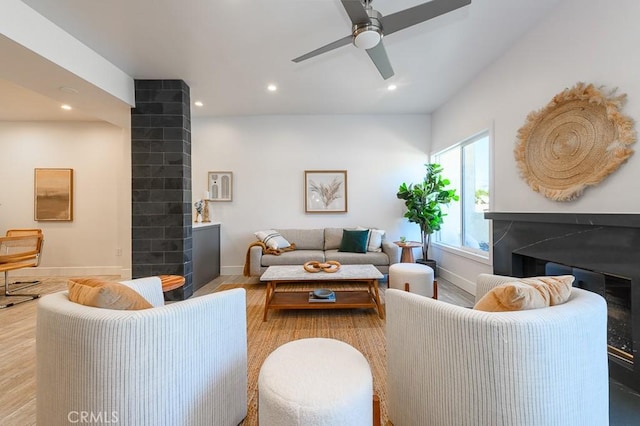 living room featuring ceiling fan, light hardwood / wood-style flooring, and a fireplace