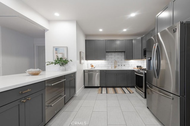 kitchen with stainless steel appliances, decorative backsplash, sink, light tile patterned floors, and gray cabinetry