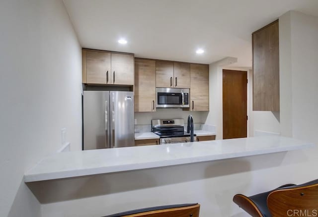 kitchen with a kitchen breakfast bar, kitchen peninsula, and stainless steel appliances