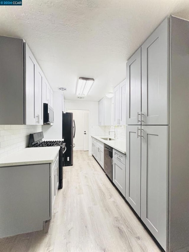 kitchen featuring stainless steel dishwasher, decorative backsplash, light hardwood / wood-style floors, and range with gas cooktop