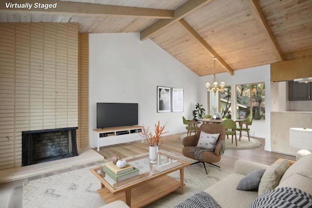 living room with light wood-type flooring, a notable chandelier, a brick fireplace, high vaulted ceiling, and beam ceiling