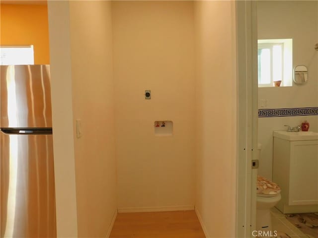 interior space featuring a sink, light wood-type flooring, and baseboards