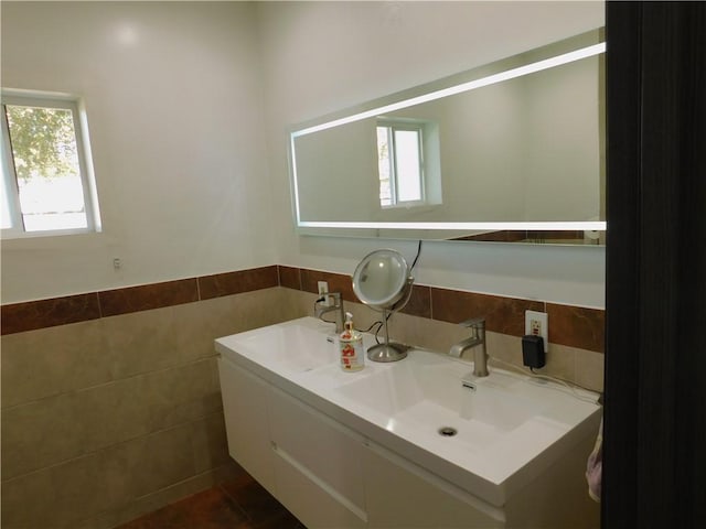 bathroom featuring a sink, tile walls, wainscoting, and double vanity