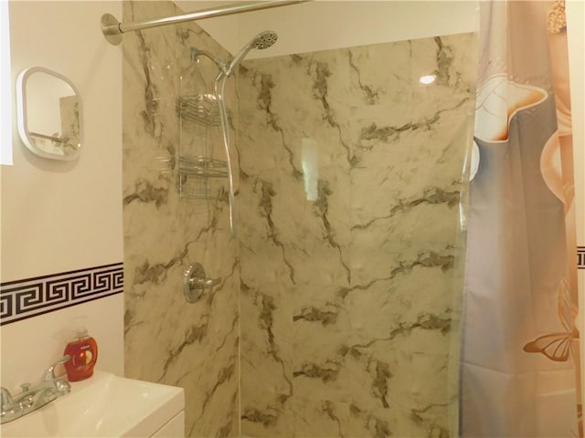 room details featuring a marble finish shower and a sink