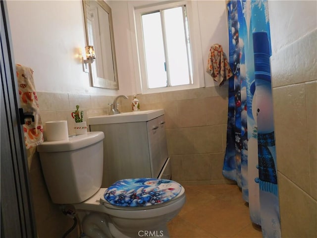 bathroom featuring vanity, a wainscoted wall, tile patterned flooring, tile walls, and toilet