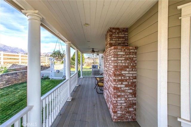 deck featuring fence, a mountain view, ceiling fan, and a porch