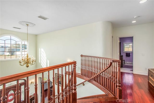 hallway with a notable chandelier, an upstairs landing, dark wood-type flooring, and visible vents