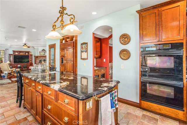 kitchen with dobule oven black, a ceiling fan, visible vents, arched walkways, and open floor plan