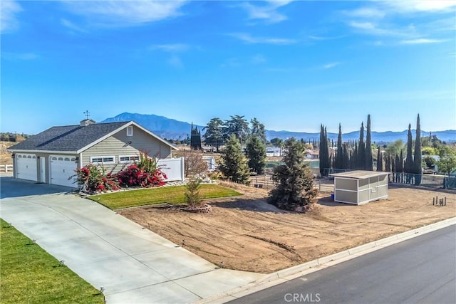 view of front of house with concrete driveway, an attached garage, fence, and a mountain view