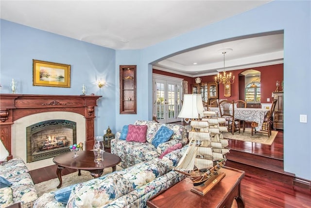 living room with arched walkways, a fireplace with flush hearth, french doors, and hardwood / wood-style flooring