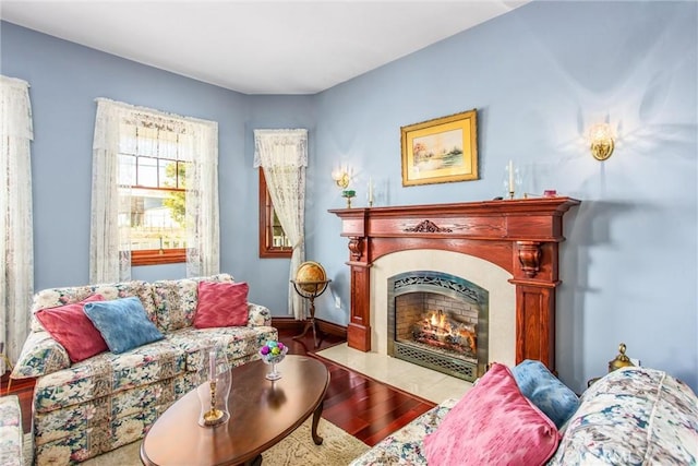 living area with baseboards, a fireplace with flush hearth, and wood finished floors
