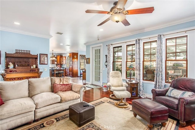 living room with visible vents, ornamental molding, ceiling fan, and wood finished floors