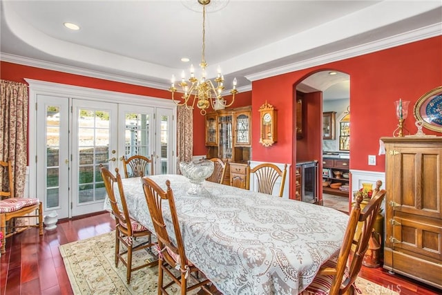 dining space with an inviting chandelier, wainscoting, beverage cooler, arched walkways, and french doors