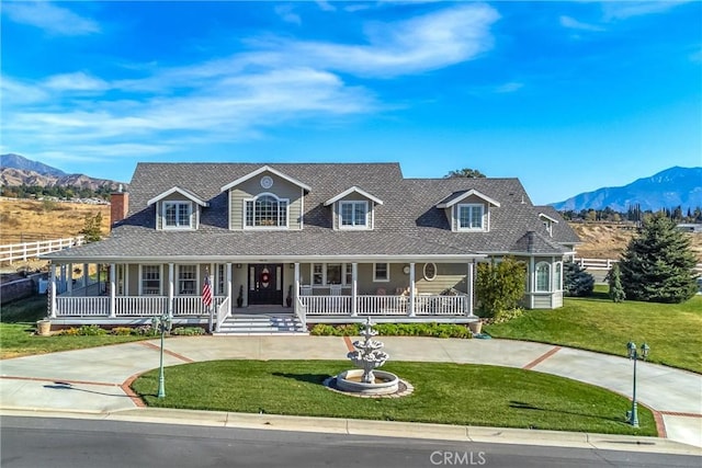 farmhouse inspired home featuring curved driveway, a mountain view, covered porch, and a front yard