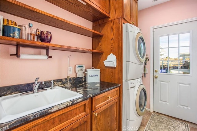 washroom with a sink, stacked washer and clothes dryer, cabinet space, and light tile patterned floors