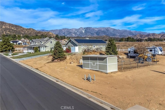 exterior space with fence, a residential view, a storage shed, a mountain view, and an outdoor structure